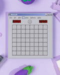 A memo pad featuring a Minesweeper inspired design on a purple backdrop with stationery items.
