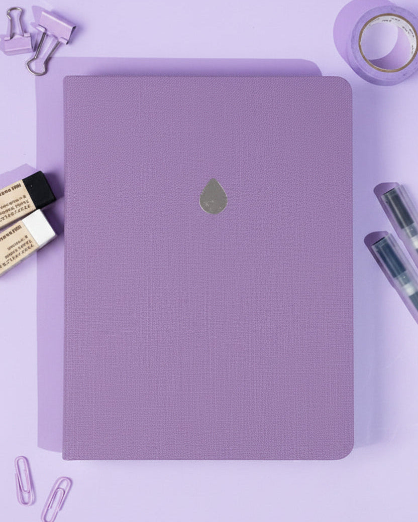 Lilac cloth notebook with a drop design on a purple background with stationery items.